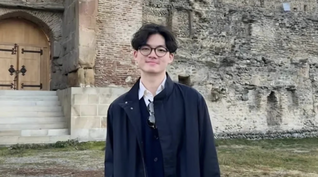 Georgetown senior, Brian Cody Wibowo, stands in front of stone building